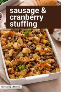 Baked pan of sausage and cranberry stuffing on a countertop. Text overlay includes recipe name.