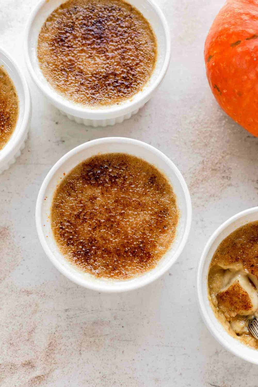 Pumpkin creme brulee custards sprinkled with sugar, ready to be bruleed