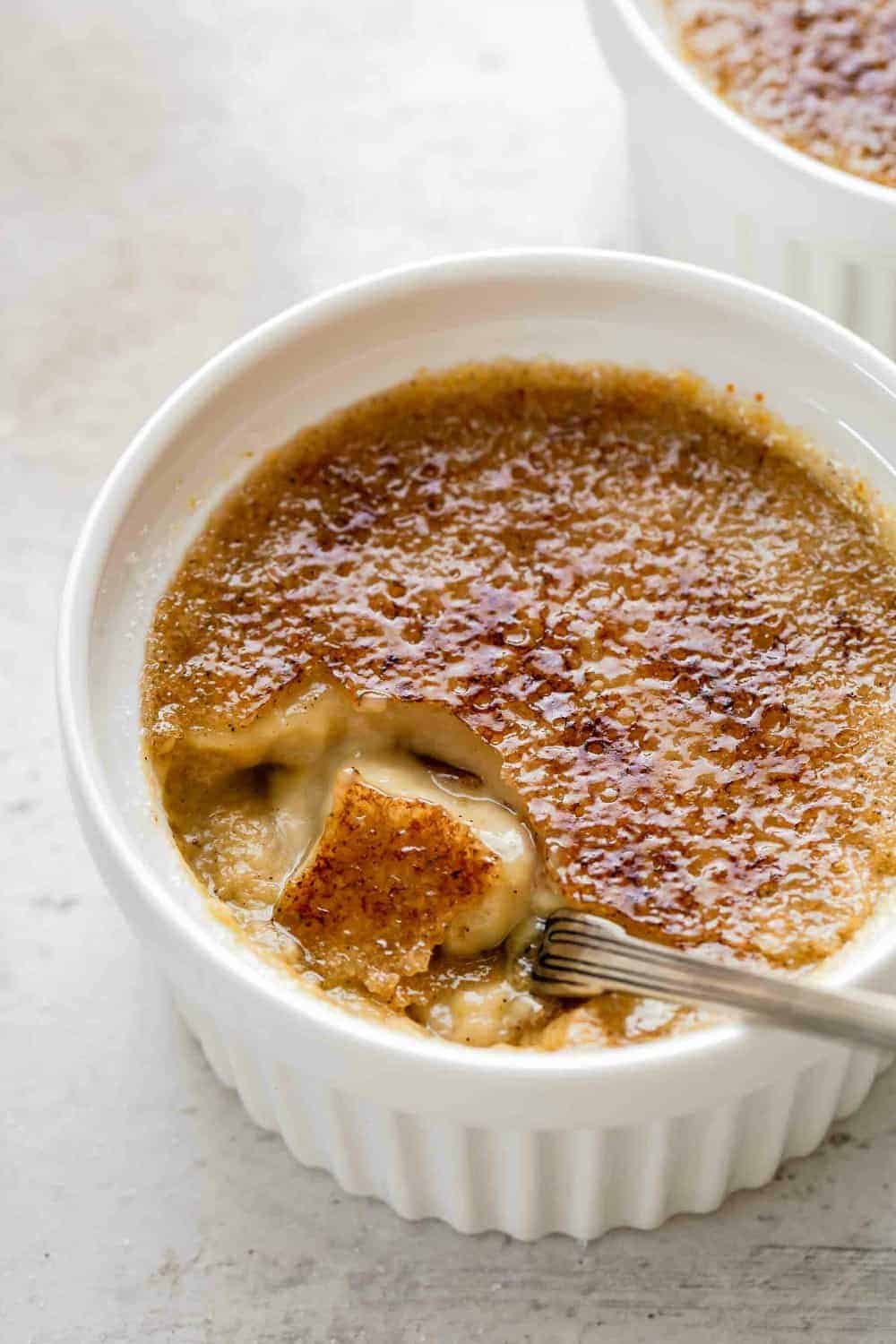 Close up of a spoon breaking into the crackly sugar topping on a pumpkin creme brulee
