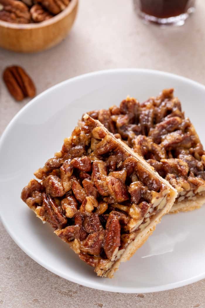Two pecan bars arranged on a white plate.