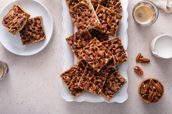 Pieces of pecan bars arranged on a white platter.