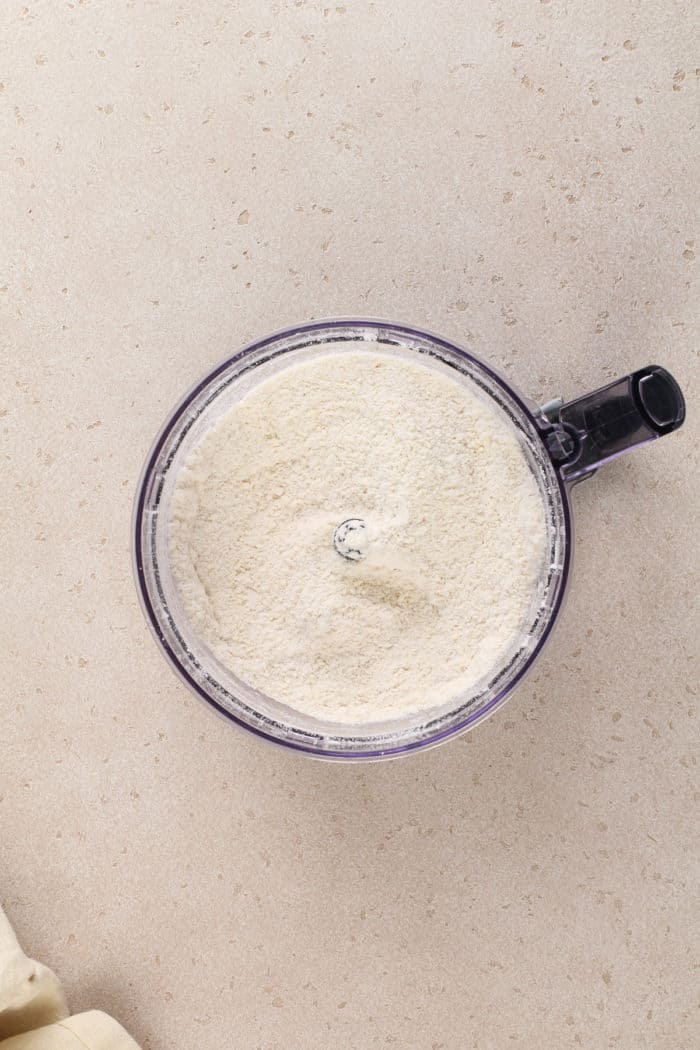 Crumbly base for shortbread crust in the bowl of a food processor.