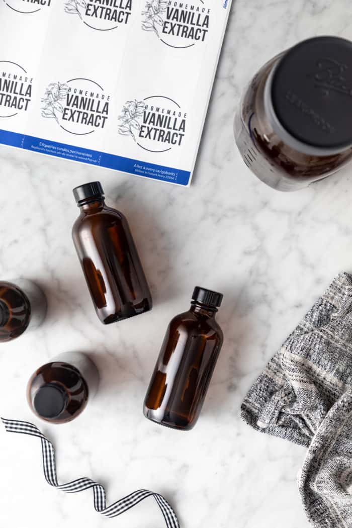 Small amber bottles and printed vanilla extract labels on a marble surface.