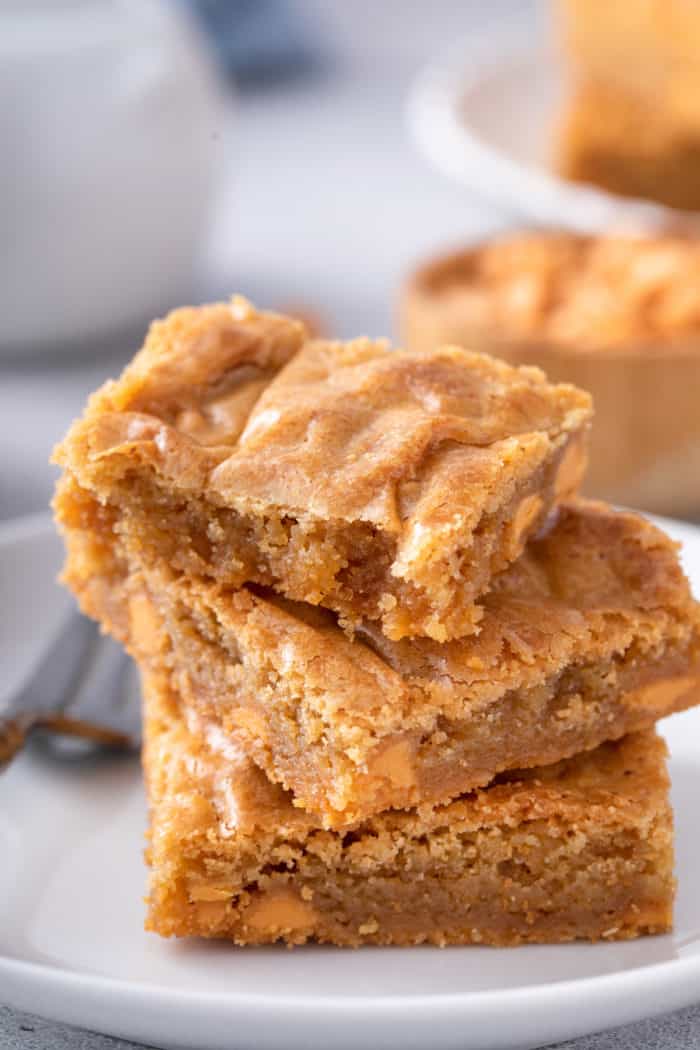 3 brown butter blondies stacked on a white plate.