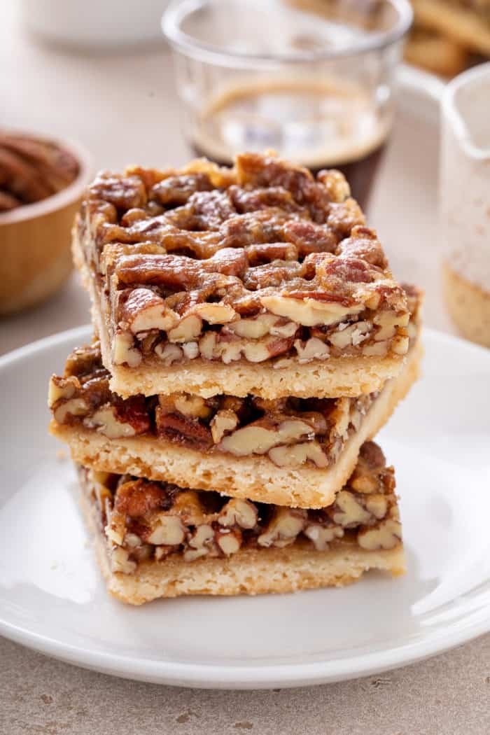 Three stacked pecan bars on a white plate.