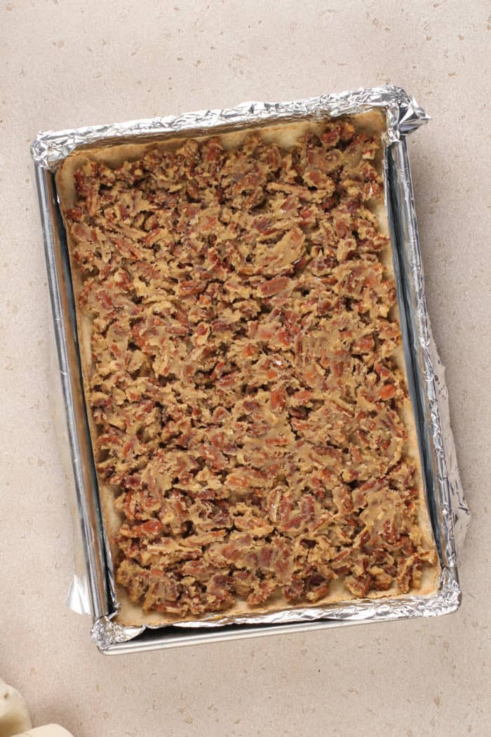 Unbaked pecan bars in a foil-lined baking dish, ready to go in the oven.