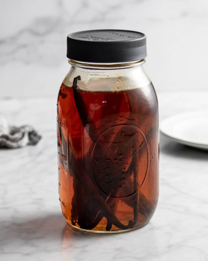 Homemade vanilla extract in a large mason jar with a black lid.