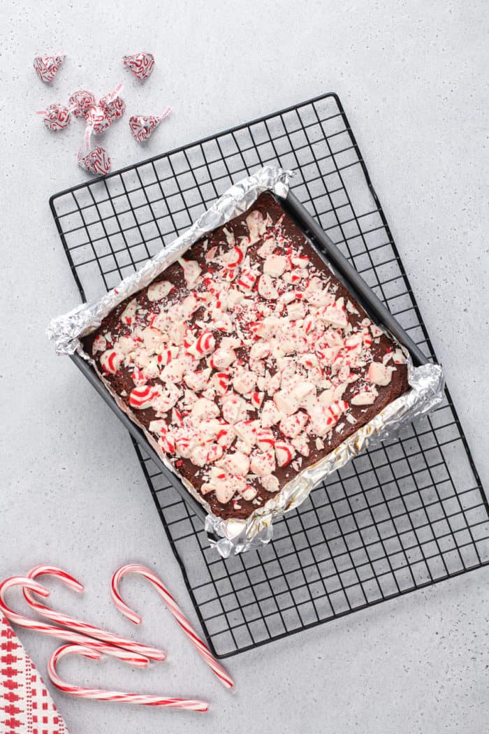 Baked peppermint brownies in a foil-lined pan, on a wire cooling rack.