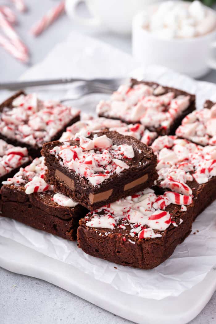 Sliced pan of peppermint brownies. One of the brownies is set on top of the rest to show the milk chocolate pieces in the center.