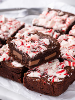 Sliced peppermint brownie set on top of a sliced pan of peppermint brownies.