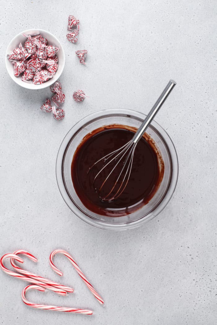 Melted chocolate and butter being whisked in a glass mixing bowl.