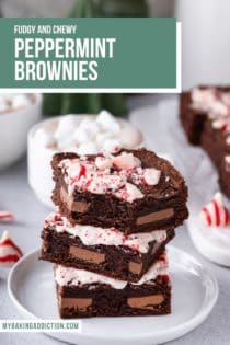 Three stacked peppermint brownies on a white plate. The top brownie has a bite taken out of it. Text overlay includes recipe name.