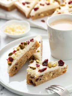 Three cranberry bliss bars arranged on a white plate, with a bite taken out of one of them