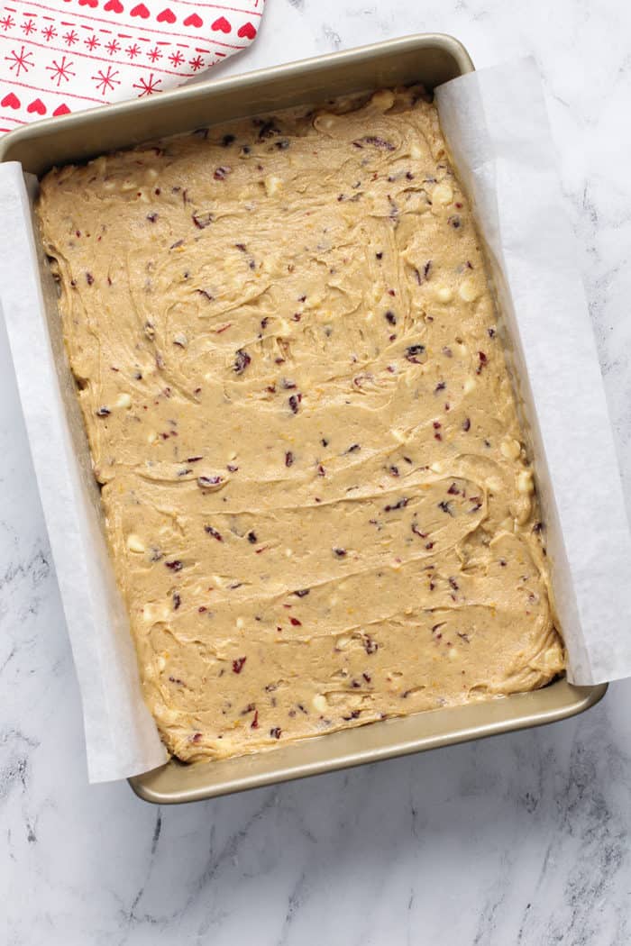 Cranberry bliss bar batter in a parchment-lined baking pan