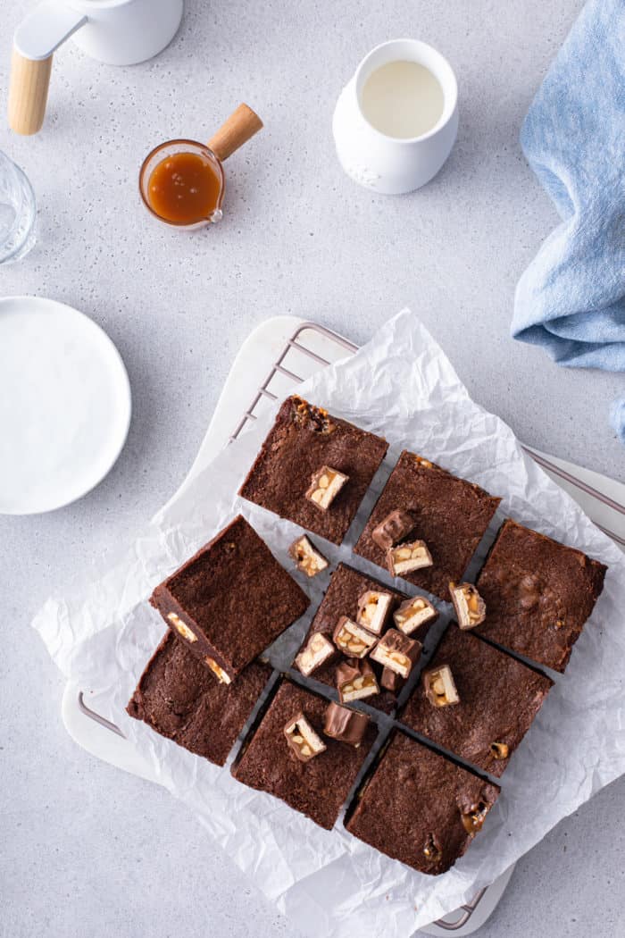 Overhead view of sliced snickers brownies set on a piece of parchment paper.