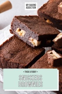Snickers brownies cut into pieces and topped with pieces of snickers candy bars. Text overlay includes recipe name.