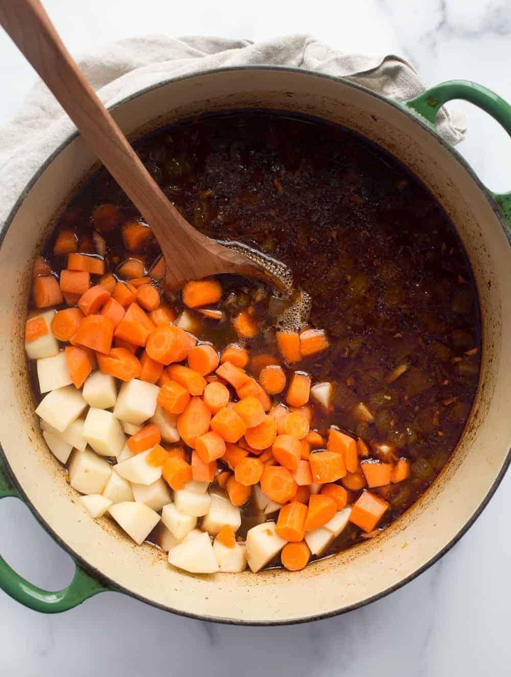 Carrots and potatoes added to Guinness stew in a Dutch oven