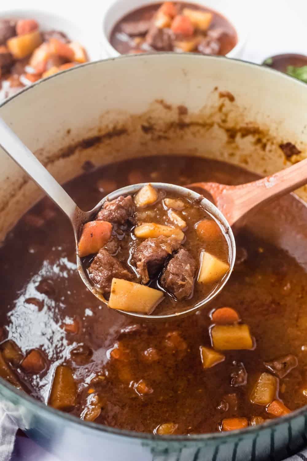Ladle serving Guinness beef stew out of a large Dutch oven
