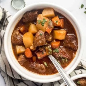 Guinness stew full of carrots and potatoes in a white bowl