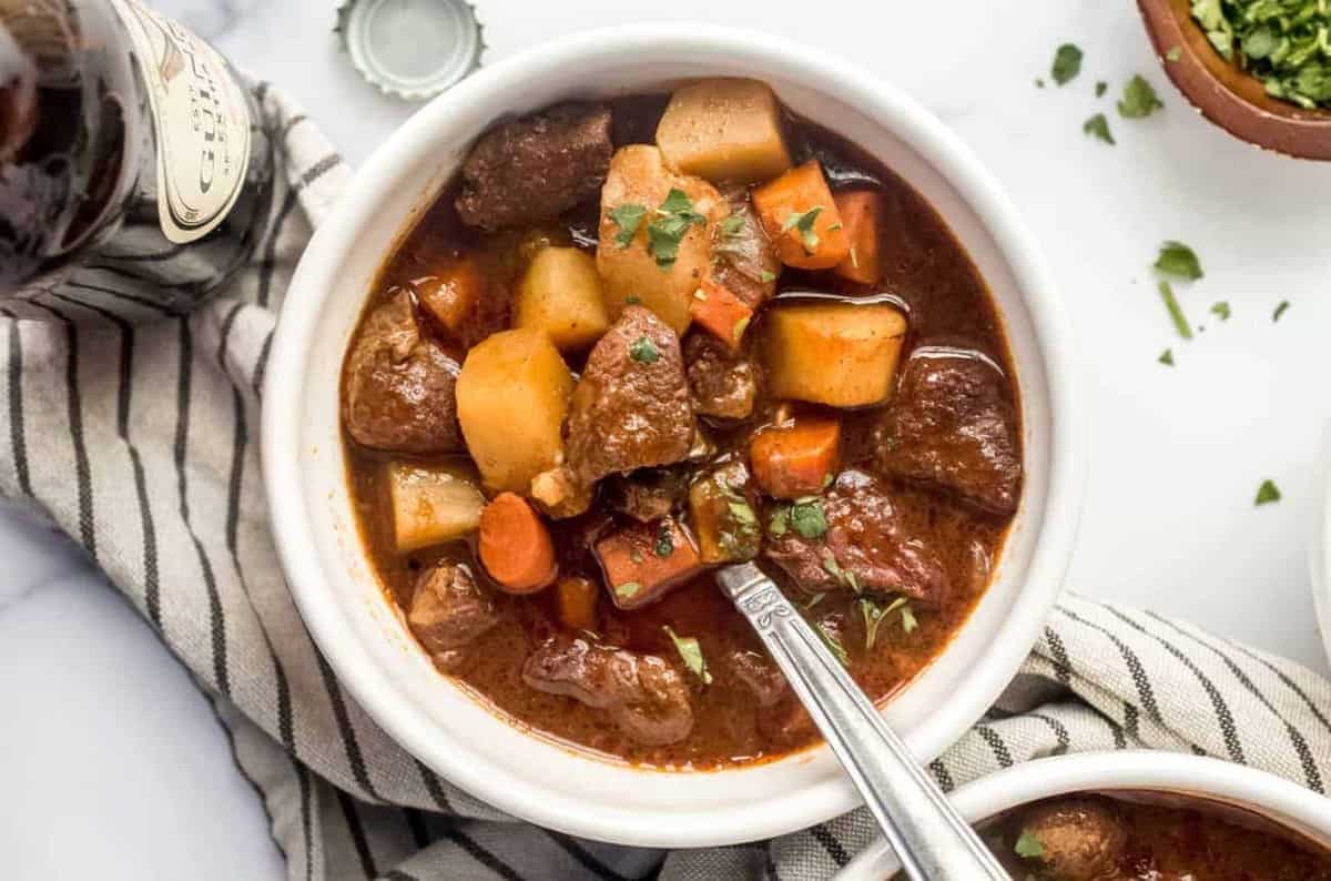 Guinness stew full of carrots and potatoes in a white bowl