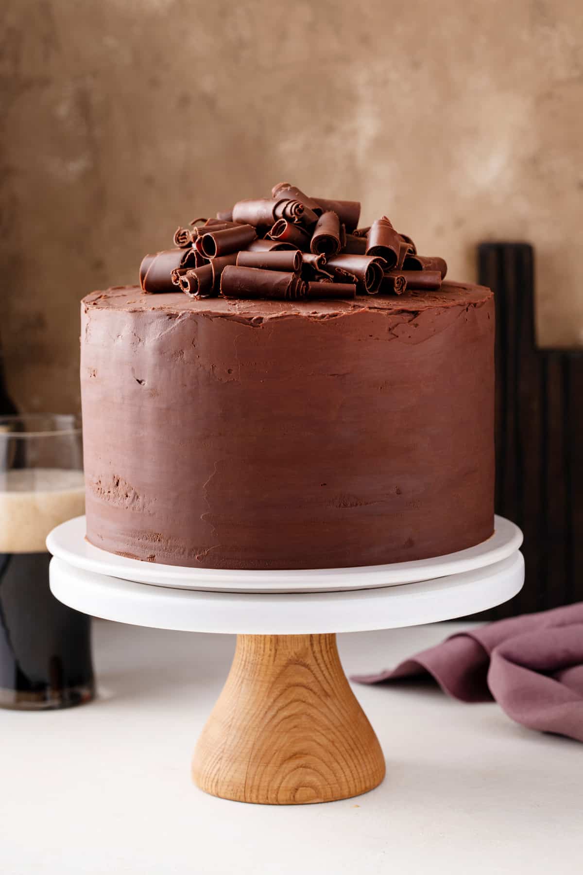 Chocolate guinness cake garnished with chocolate curls set on a cake stand.
