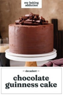Chocolate guinness cake garnished with chocolate curls set on a cake stand. Text overlay includes recipe name.