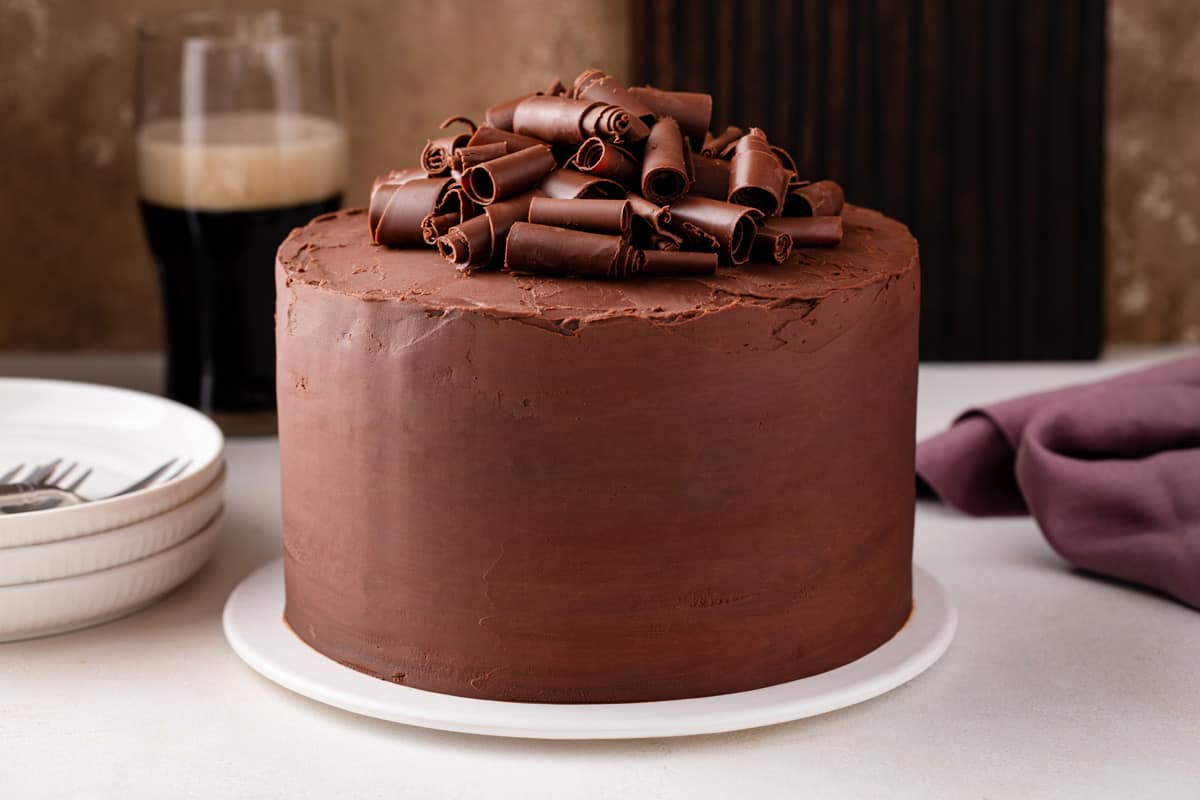 Frosted chocolate guinness cake on a white cake plate.