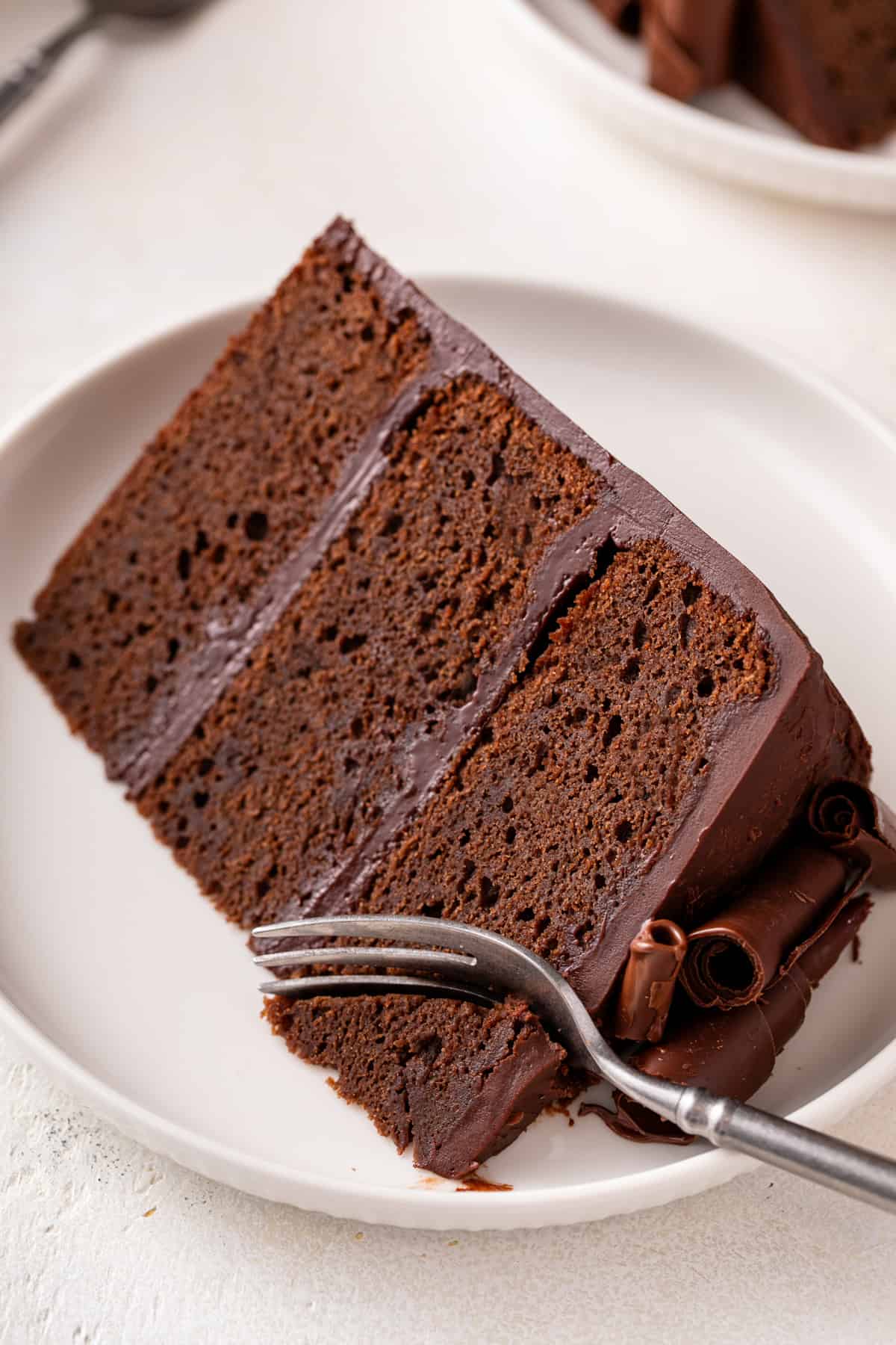 Fork cutting a bite from the corner of a slice of chocolate guinness cake.