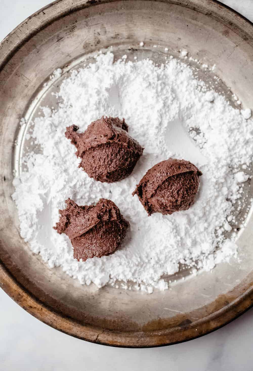 Dough for chocolate crinkle cookies ready to be rolled in powdered sugar