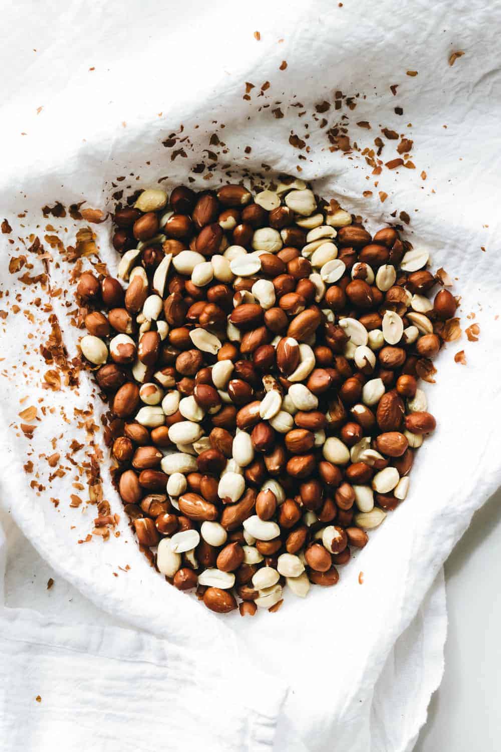 Toasted peanuts in a white dish towel to remove the skins