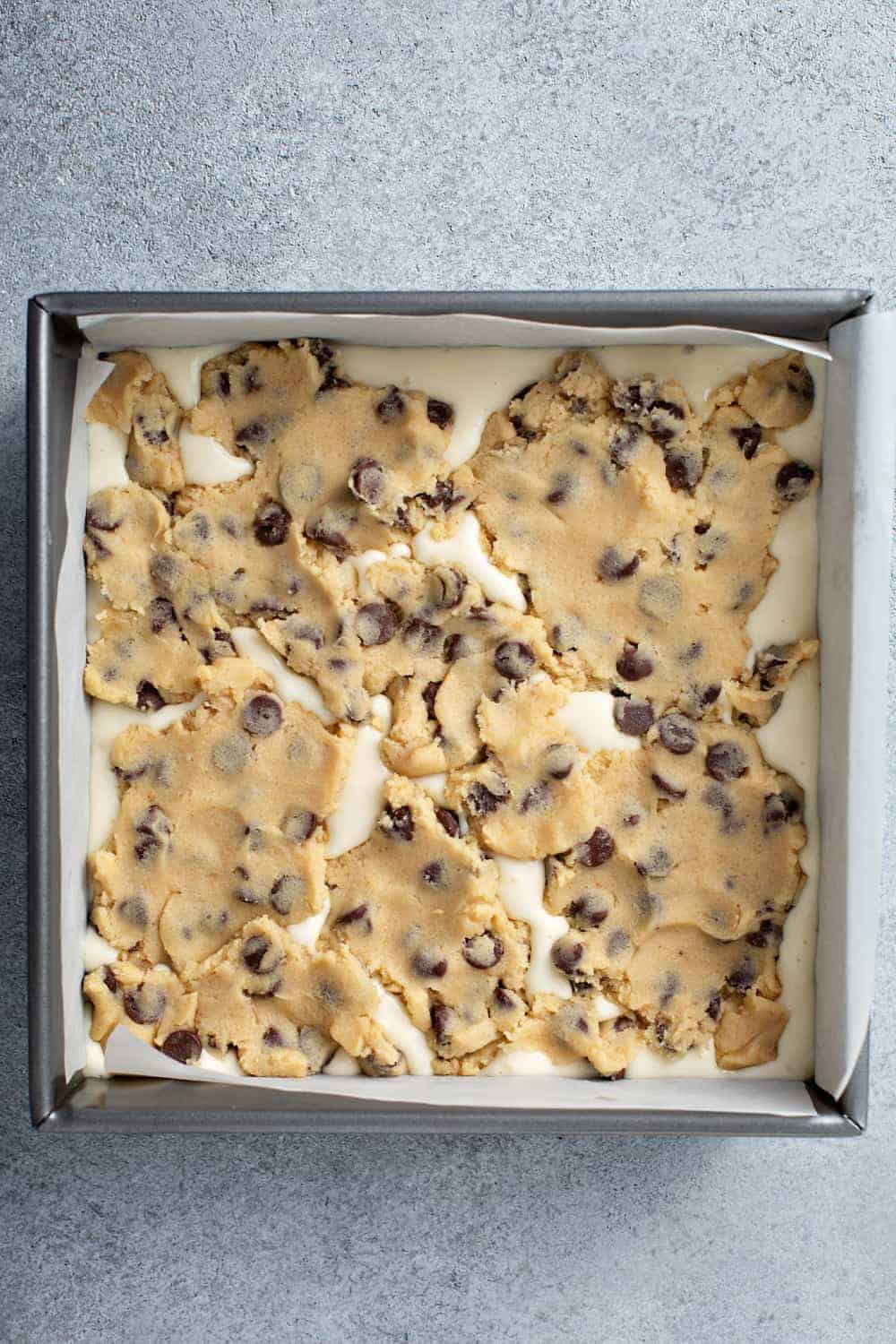 Cookie dough cheesecake bars in a pan, ready to bake