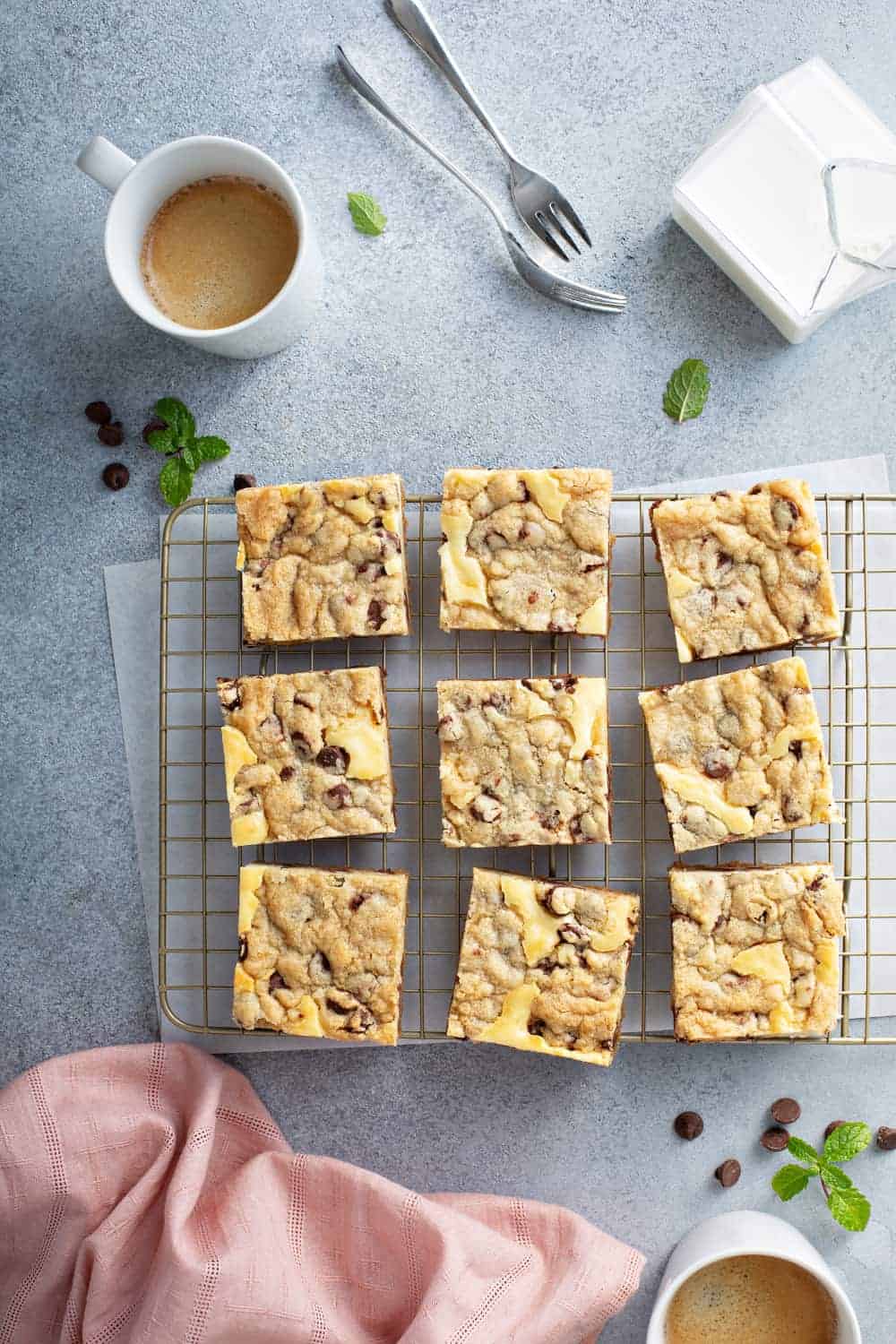 Overhead shot of sliced cookie dough cheesecake bars on a cooling rack