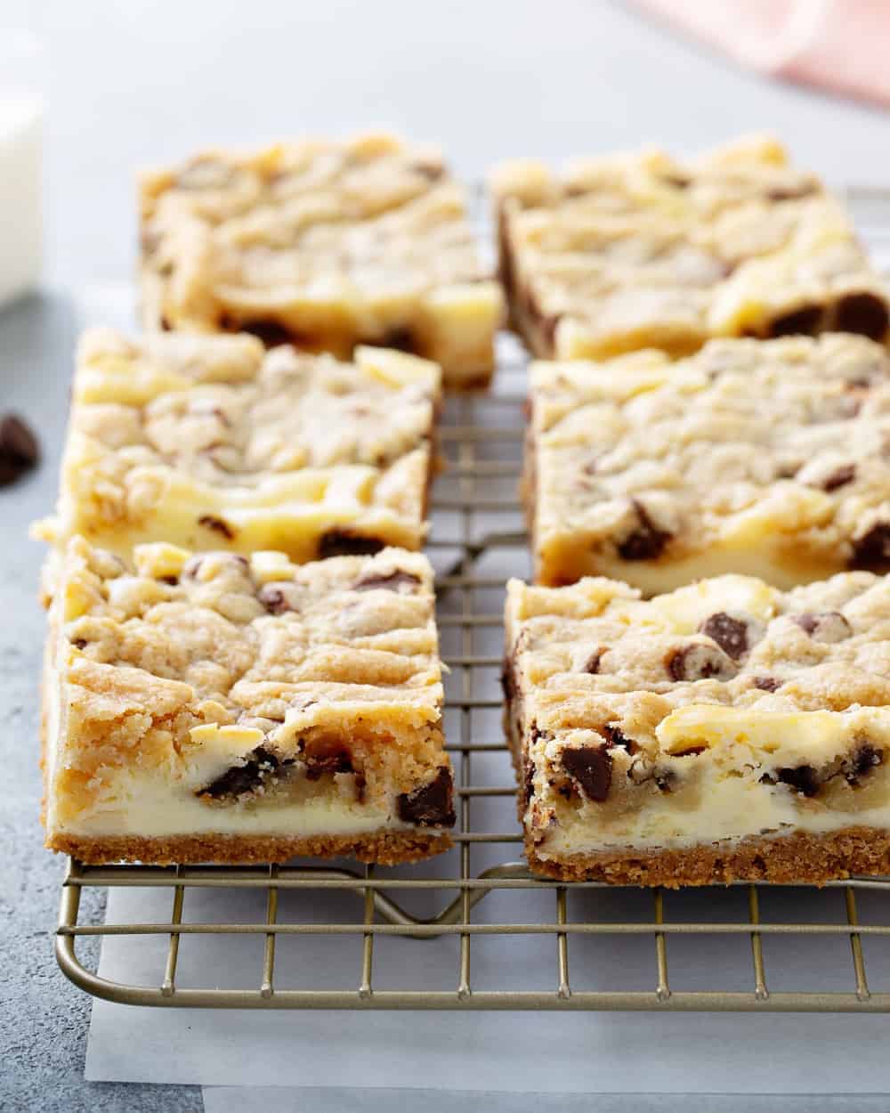 Close up of sliced cookie dough cheesecake bars on a cooling rack