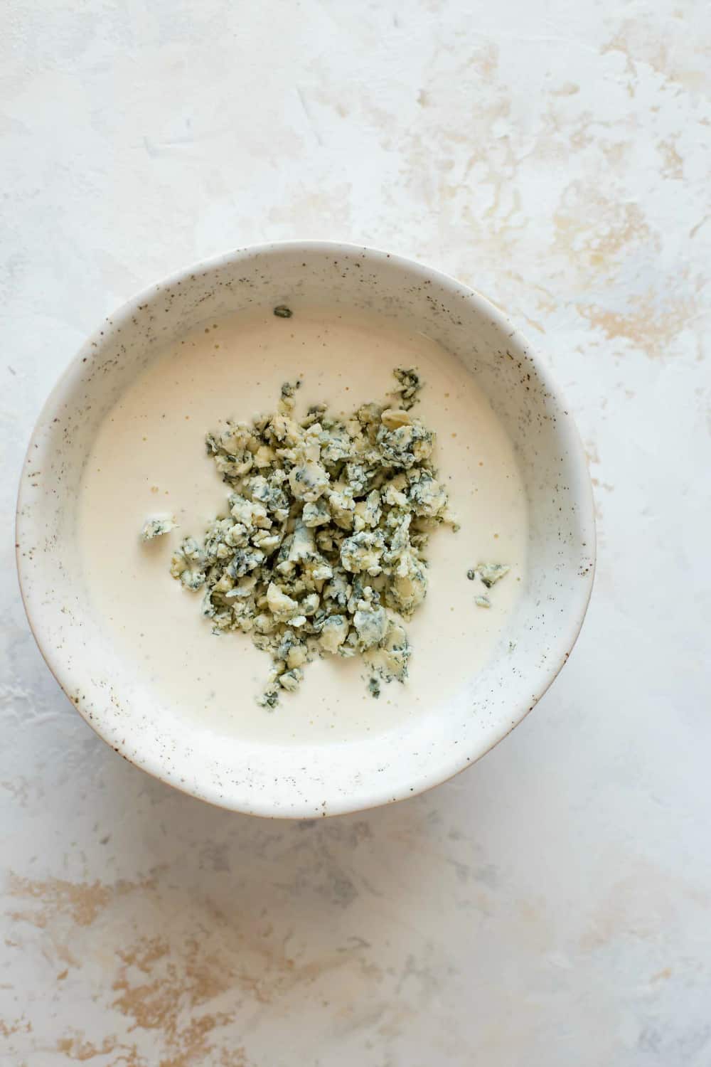 Homemade blue cheese dressing in a bowl with blue cheese crumbles