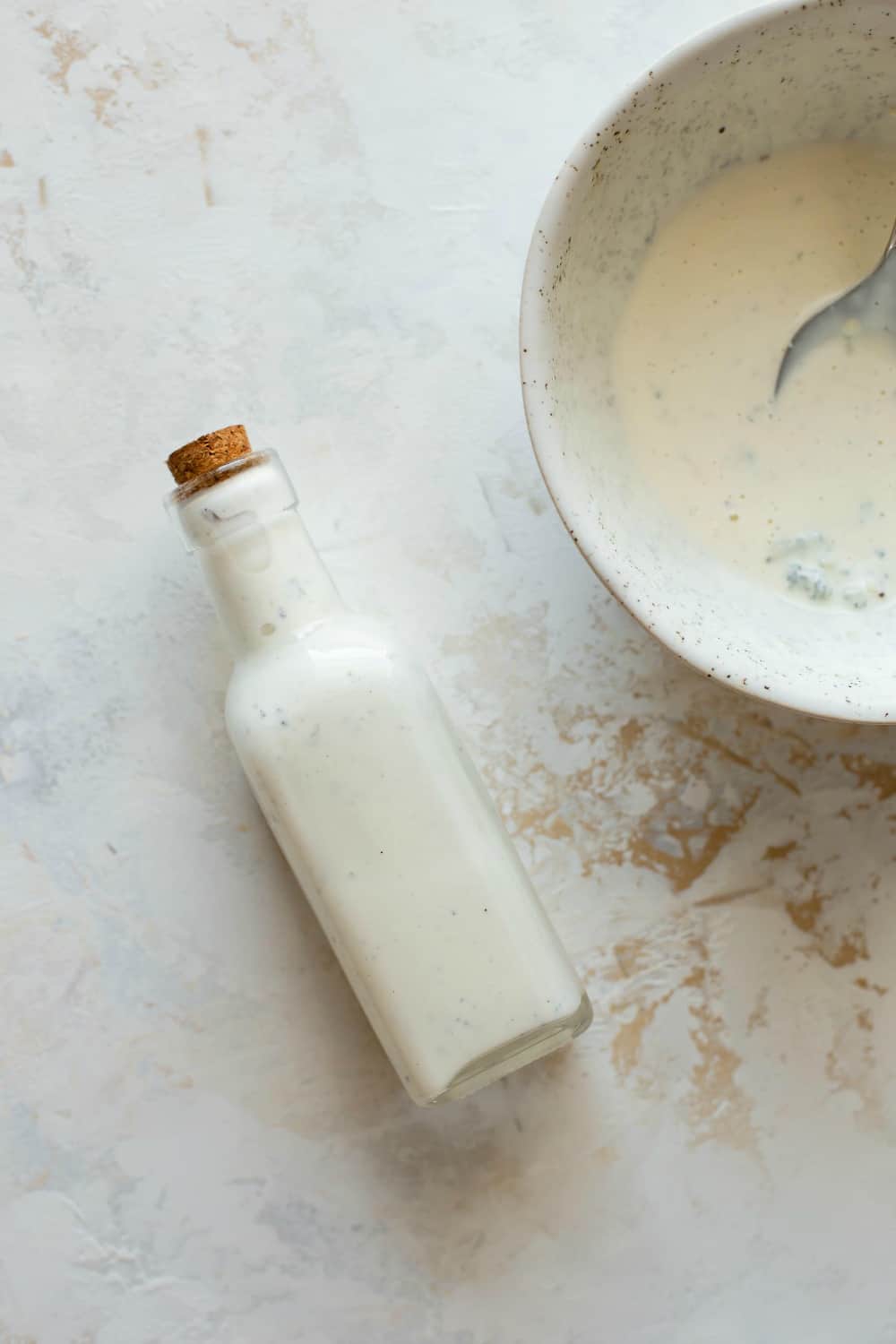 Bottle of blue cheese dressing next to a bowl of blue cheese dressing