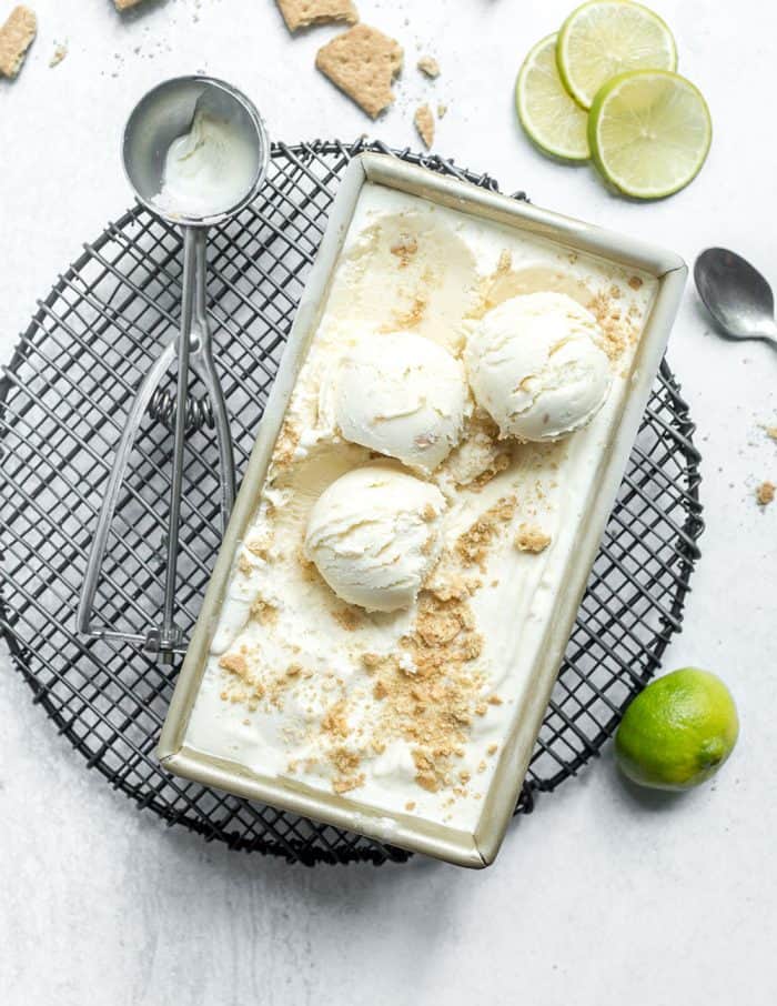 Loaf pan with key lime pie ice cream set on a marble counter next to an ice cream scoop