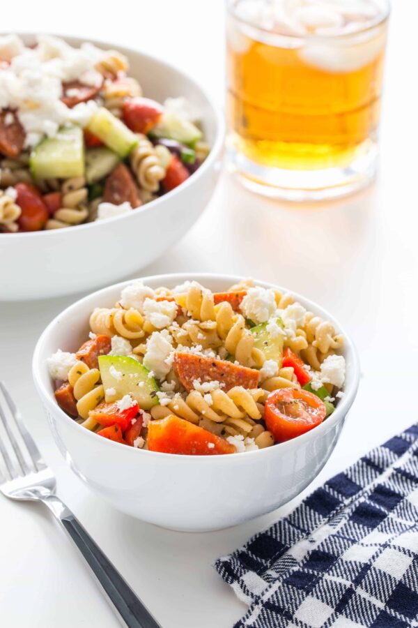 Greek Pasta Salad is loaded with fresh vegetables, feta cheese, pepperoni and a homemade Greek dressing to create the best pasta salad you'll ever eat. Perfect for summer barbecues!