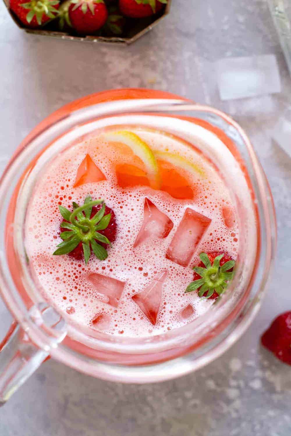 Overhead of pitcher of strawberry lemonade with whole berries and sliced lemons in it