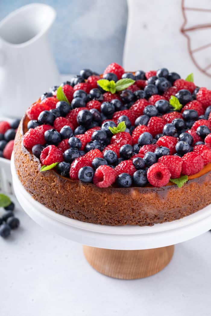 Ricotta cheesecake topped with rows of red and blue berries.