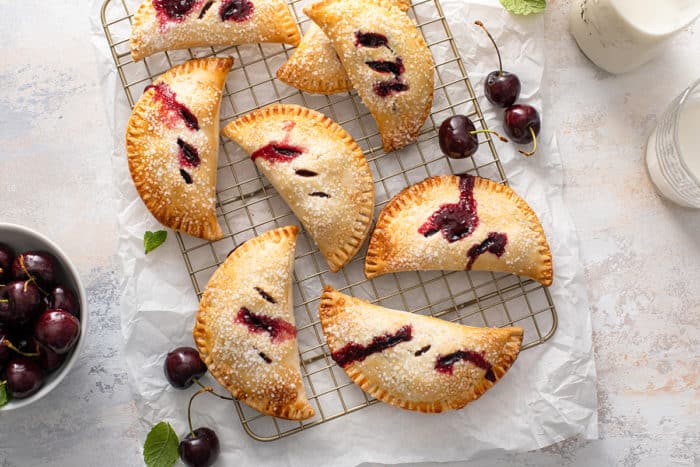 Overhead view of baked cherry hand pies cooling on a wire rack