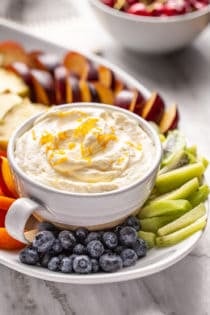 Bowl of orange fruit dip set on a platter of fresh fruit