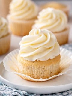 Vanilla cupcake unwrapped on a white plate.