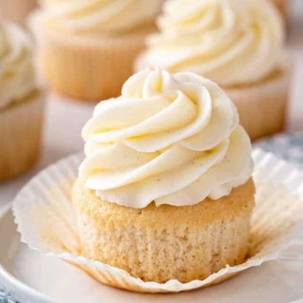 Vanilla cupcake unwrapped on a white plate.