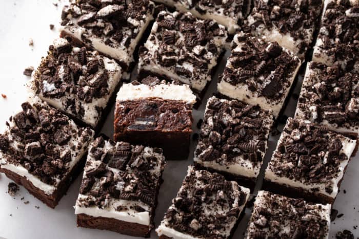 Close up of sliced oreo brownies topped with vanilla frosting and chopped oreo pieces.