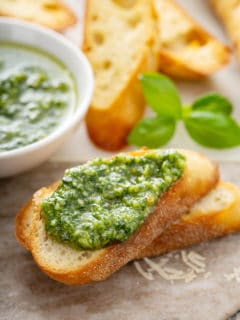 Fresh basil pesto spread on top of a slice of baguette