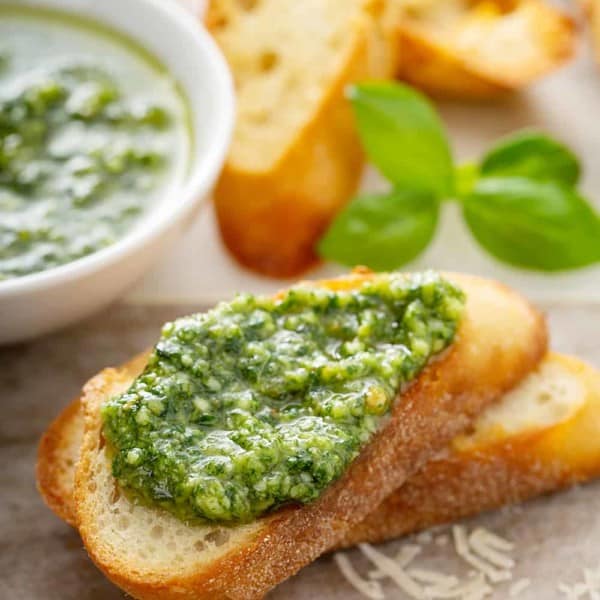 Fresh basil pesto spread on top of a slice of baguette