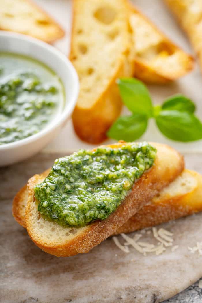 Fresh basil pesto spread on top of a slice of baguette