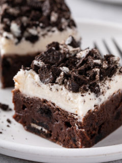 Oreo brownie topped with vanilla frosting on a white plate.