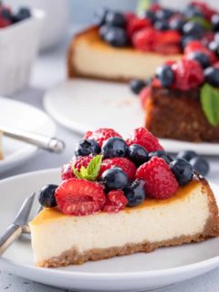 Plated slice of ricotta cheesecake, topped with raspberries and blueberries.