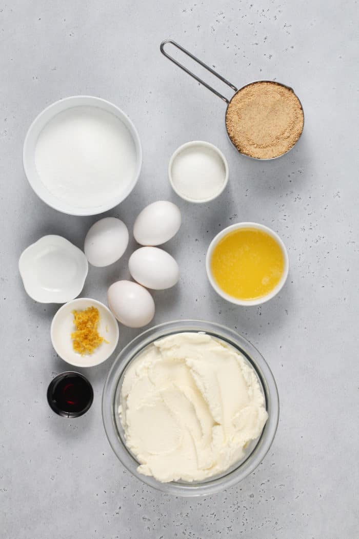 Ingredients for ricotta cheesecake arranged on a light gray countertop.
